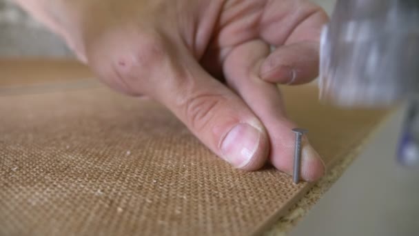 Un hombre recoge muebles en un taller. 4k, cámara lenta. Fijación y montaje de muebles en los pasadores de madera — Vídeos de Stock