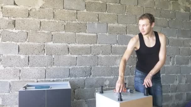 Мужчина собирает мебель в мастерской. 4К, замедленная съемка. Связывание и монтаж мебели на деревянных булавках — стоковое видео