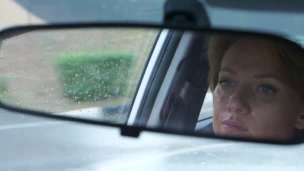 Reflection of a womans face with blue eyes in rearview mirror, woman behind the wheel. 4k, slow motion — Stock Video