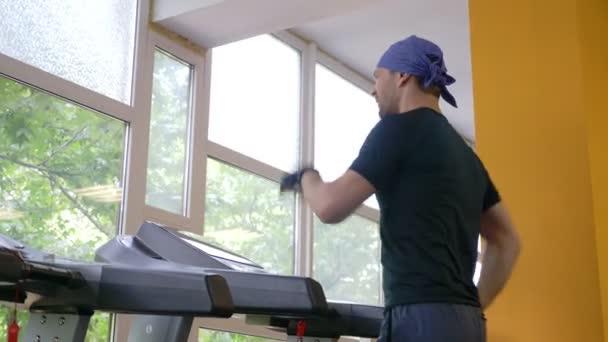 Ładny facet działa na bieżni w siłowni. 4k, zwolnionym tempie — Wideo stockowe