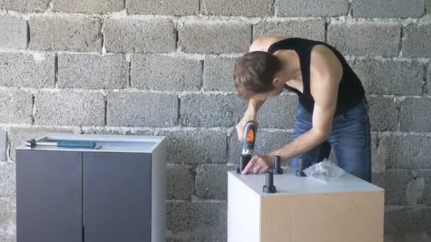 Un hombre recoge muebles en un taller. 4k, cámara lenta. Fijación y montaje de muebles en los pasadores de madera — Vídeos de Stock