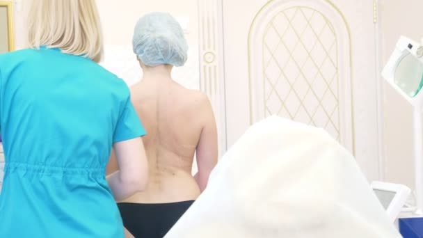 太い女性は脂肪吸引医療を準備します。医師は、マーカー、背面にマークを描画します。4 k — ストック動画
