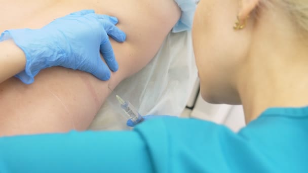 Le médecin le dermatologue le cosmétique introduit la lipolitique au moyen d'une seringue dans les plis gras sur le dos de la femme du patient. 4k — Video