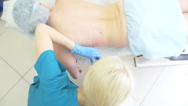 Le médecin le dermatologue le cosmétique introduit la lipolitique au moyen d'une seringue dans les plis gras sur le dos de la femme du patient. 4k — Video