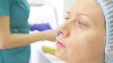 Hijyenik şapkalı bir kadın hasta yordamı doktor ofisinde bekliyor. yakın çekim. 4k