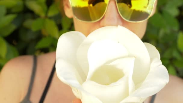 Une belle fleur de magnolia blanc dans les mains d'une femme au visage. reflet dans les lunettes de soleil, gros plan. 4k, au ralenti — Video