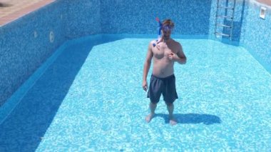 boş bir yüzme havuzu Şnorkelle Dalma maskesi ve şnorkel içine komik bir genç adam tırmanıyor. 4 k. mizah.