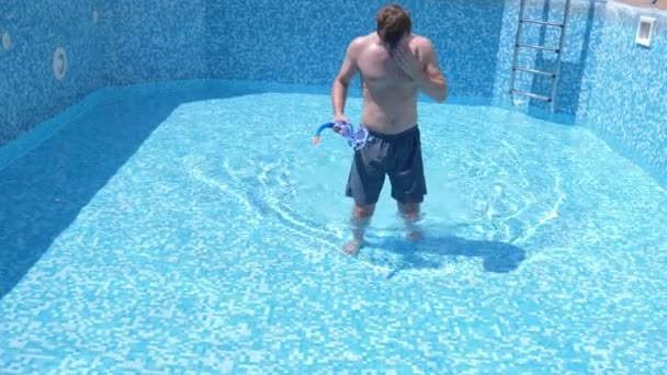 En ung rolig kille klättrar in i en tom pool med snorkling mask och snorkel. 4 k. humor. — Stockvideo