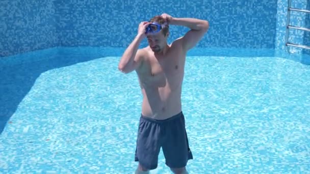 Een jonge grappige kerel klimt in een lege zwembad met een snorkelen masker en snorkel. 4 k. humor. — Stockvideo