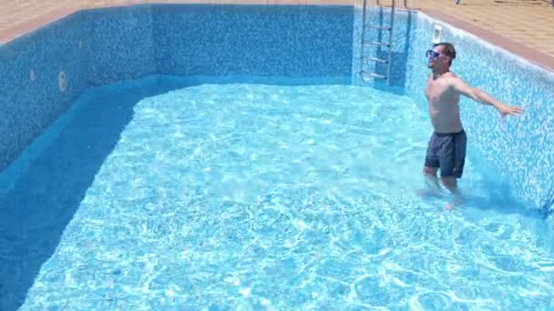一个年轻有趣的家伙爬上一个空的游泳池与潜水面罩和浮潜。4k. 幽默. — 图库视频影像