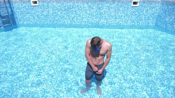 Seorang pemuda lucu memanjat ke kolam renang kosong dengan topeng snorkelling dan snorkel. 4k. humor . — Stok Video