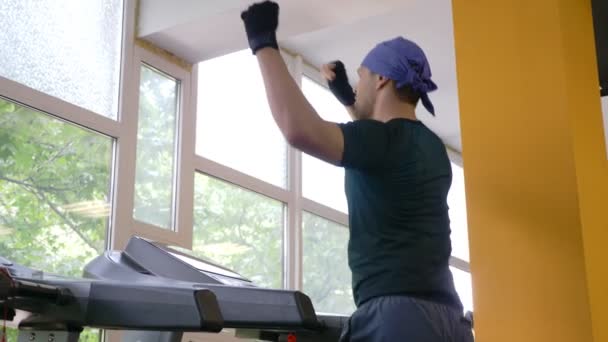 Un mec mignon court sur un tapis roulant dans la salle de gym. 4k, au ralenti — Video