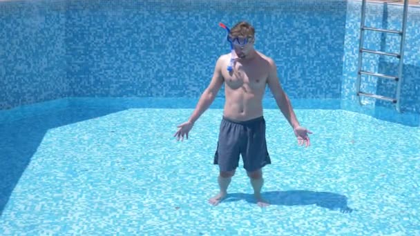 A young funny guy climbs into an empty swimming pool with a snorkelling mask and snorkel. 4k. humor. — Stock Video