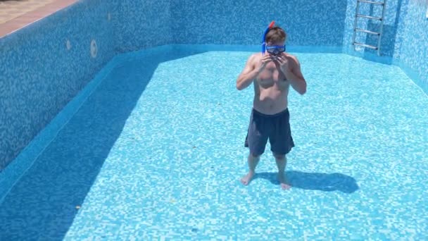 Un joven divertido se mete en una piscina vacía con una máscara de snorkel y snorkel. 4k. humor . — Vídeos de Stock