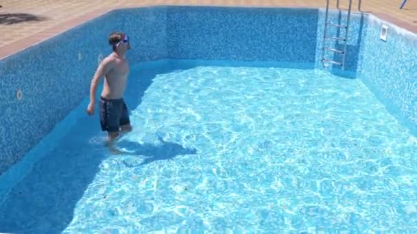 一个年轻有趣的家伙爬上一个空的游泳池与潜水面罩和浮潜。4k. 幽默. — 图库视频影像