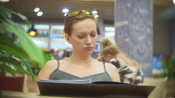 Mujer mirando el menú en el restaurante, pasando páginas y la elección de platos para la cena evento almuerzo citas, 4k, cámara lenta — Vídeos de Stock