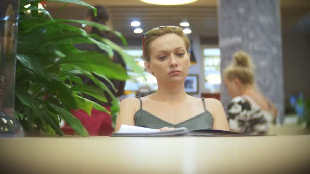 Женщина смотрит меню в ресторане, переворачивает страницы и выбирает тарелки для ужина обед знакомства, 4k, замедленной съемки — стоковое видео