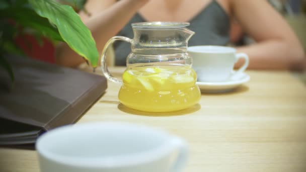 La donna al bar sta bevendo tè al limone allo zenzero. teiera trasparente, 4k, ripresa al rallentatore — Video Stock