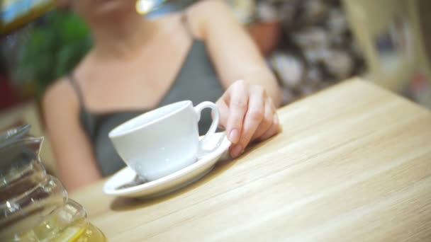 La mujer en el café está bebiendo té de limón de jengibre. tetera transparente, 4k, disparo en cámara lenta — Vídeo de stock