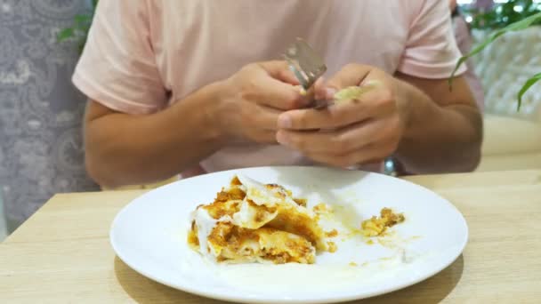 Un hombre come lasaña en un restaurante con tenedor y cuchillo. Primer plano. 4k, cámara lenta — Vídeos de Stock