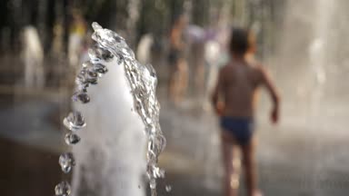 Çocuk su şehir Çeşme akışında oyun. Yaz Güney. 4k, ağır çekim, görüntü