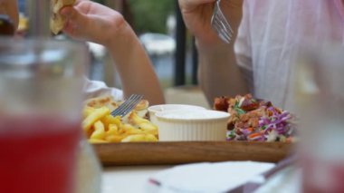 Baba ve küçük kızı bir açık hava Kafe Yunan yemekleri, souvlaki yeme. yakın çekim. 4k, ağır çekim