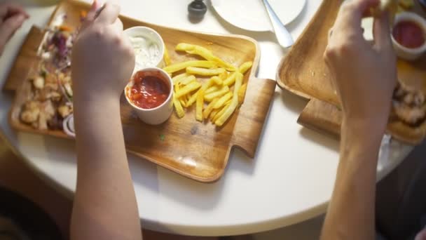 Una pareja, comiendo en un café al aire libre platos griegos, souvlaki y cerveza. 4k, cámara lenta — Vídeo de stock