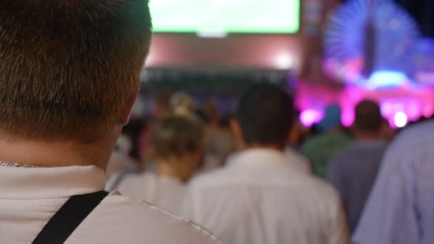 Las fiestas populares, la fiesta, la gente mira el escenario y en la pantalla en la plaza de la ciudad por la noche. 4k. difuminación — Vídeo de stock