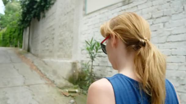 Parte posterior de la mujer en vestido azul que va a lo largo de la pared blanca. 4k — Vídeos de Stock