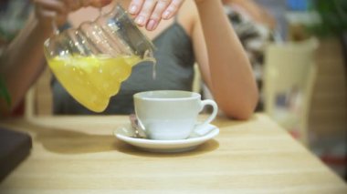 Kafedeki kadına Zencefil limon çay içiyor. şeffaf Çaydanlık, 4k, ağır çekim çekim