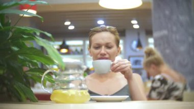 Kafedeki kadına Zencefil limon çay içiyor. şeffaf Çaydanlık, 4k, ağır çekim çekim