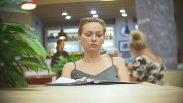 Woman looking at menu in restaurant, turning pages and choosing plates for dinner lunch event dating, 4k, slow motion — Stock Video