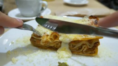 bir adam bir çatal ve bıçak ile bir restoranda lazanya yemek yer. yakın çekim. 4k, ağır çekim