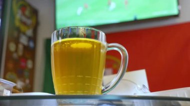 Yerel barda televizyonda futbol maçı izliyor. Gıda, bira. bir kupa bira odak ile bir Tv ekranında bir yayın bir futbol ile bulanıklık. 4k