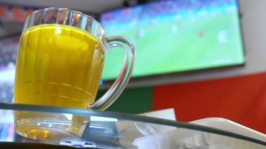 Yerel barda televizyonda futbol maçı izliyor. Gıda, bira. bir kupa bira odak ile bir Tv ekranında bir yayın bir futbol ile bulanıklık. 4k