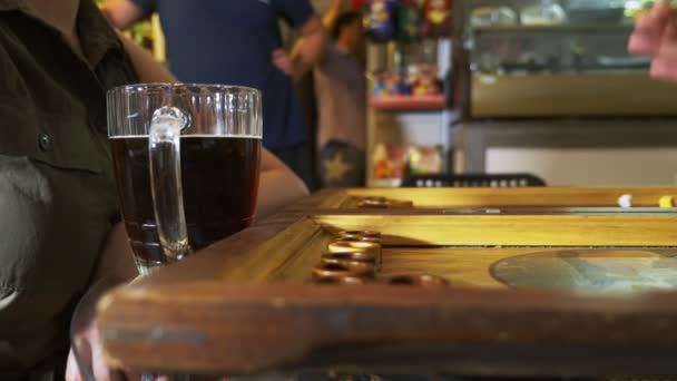 Detalle de un juego de backgammon con dos dados de cerca. Manos femeninas y masculinas tirando dos dados y damas en movimiento a bordo. Jóvenes jugando al backgammon mientras se relajan. 4k, cámara lenta — Vídeo de stock