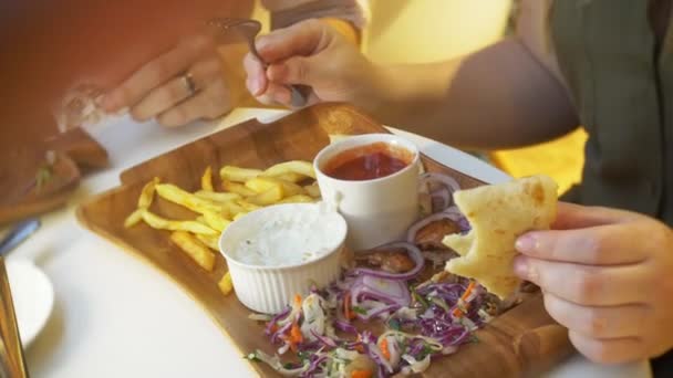 Una pareja, comiendo en un café al aire libre platos griegos, souvlaki y cerveza. 4k, cámara lenta — Vídeos de Stock