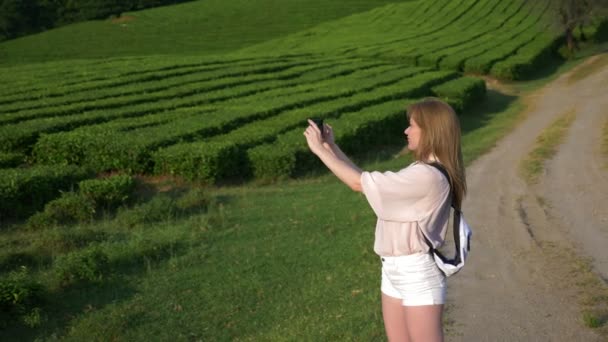 Lycklig kvinna, en bloggare gör foton och videor på sin telefon för sociala nätverk medan promenader genom en teplantage under en utflykt. begreppet resor, fritid. Life style. 4k. — Stockvideo