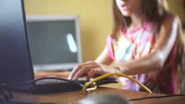 küçük kız esmer kulaklıklar, uzun saçlı bilgisayar başında oturan şarkı söylüyor. 4k, ağır çekim