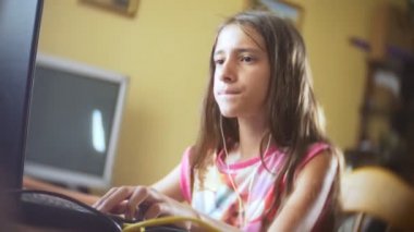 küçük kız esmer kulaklıklar, uzun saçlı bilgisayar başında oturan şarkı söylüyor. 4k, ağır çekim