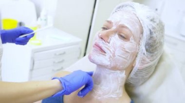 Güzellik uzmanı Doktor hastanın kontur Plasti prosedürü önce yüzünde anestezi krem uygulanır. 4k