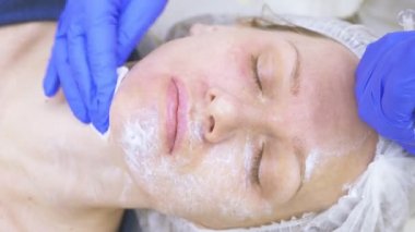 Güzellik uzmanı Doktor hastanın kontur Plasti prosedürü önce yüzünde anestezi krem uygulanır. 4k