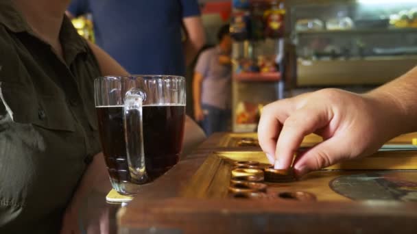 Detalle de un juego de backgammon con dos dados de cerca. Manos femeninas y masculinas tirando dos dados y damas en movimiento a bordo. Jóvenes jugando al backgammon mientras se relajan. 4k, cámara lenta — Vídeo de stock