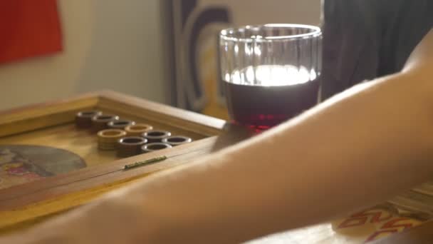 Detalj av en backgammonspel med två tärningar närbild. Kvinnliga och manliga händer rullande två tärningar och flyttar pjäser ombord. Ungdomar spelar backgammon medan du kopplar av. 4k, Slowmotion — Stockvideo