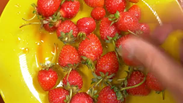 Hände nehmen eine rote reife Erdbeere aus einem gelben Teller, 4k, Zeitraffer — Stockvideo