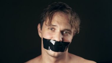 Genç adam bantlanmış ağızlı. siyah bir arka plan üzerinde. 4k.