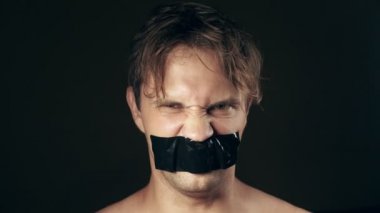 Genç adam bantlanmış ağızlı. siyah bir arka plan üzerinde. 4k.