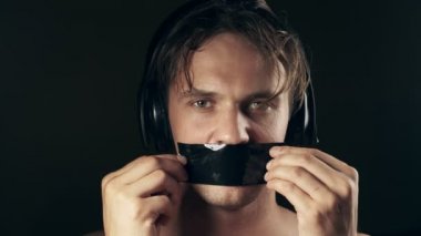 Genç adam bantlanmış ağızlı. siyah bir arka plan üzerinde. 4k.