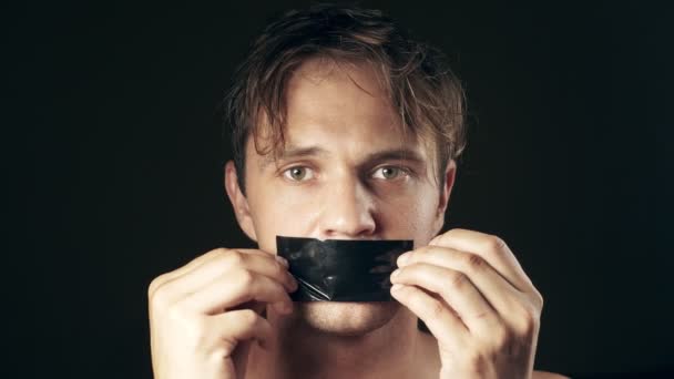 Mladý muž s lepenými ústy. na černém pozadí. 4k. — Stock video