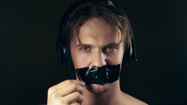 Young man with taped mouth. on a black background. 4k. — Stock Video